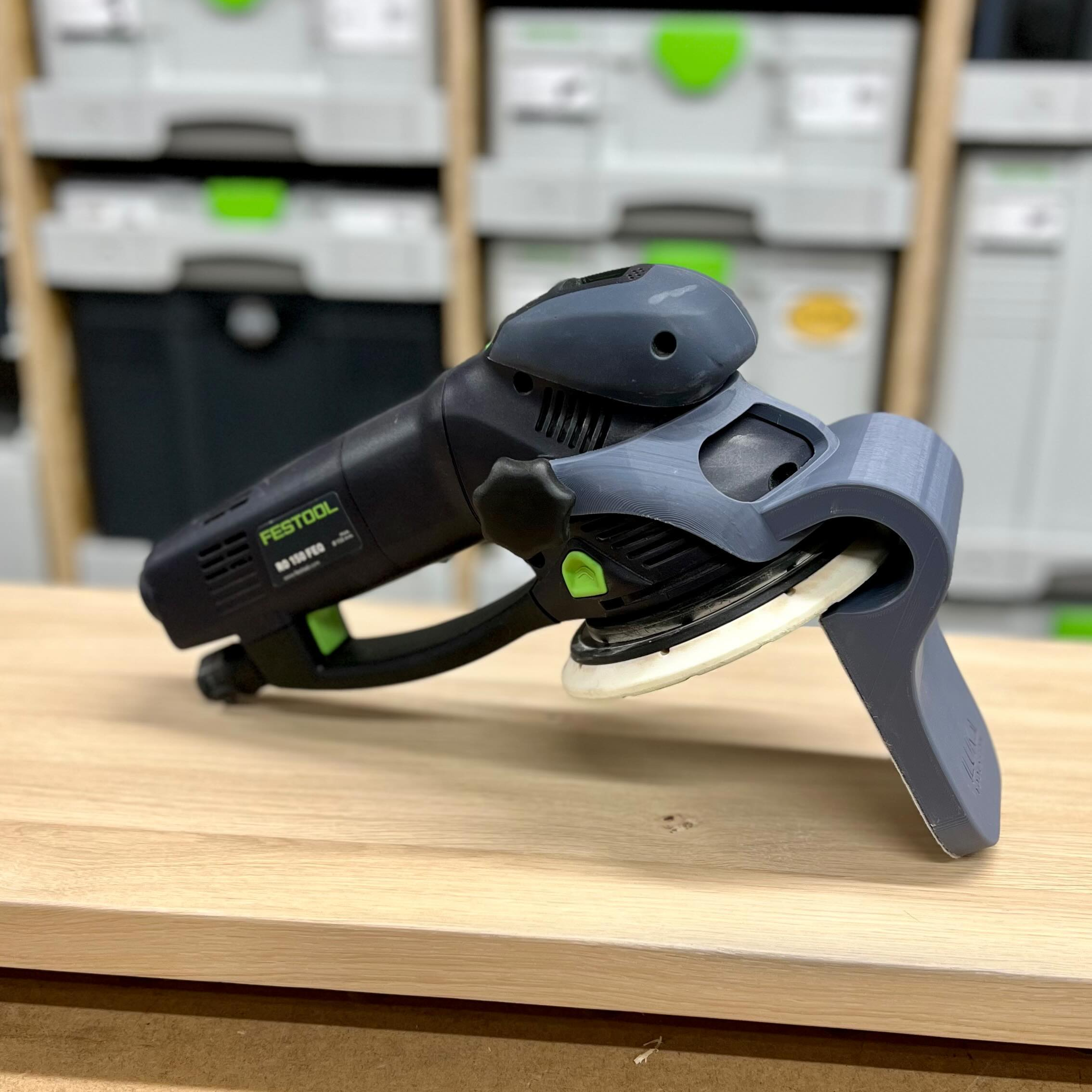 Handheld power tool on a wooden surface with storage boxes in the background